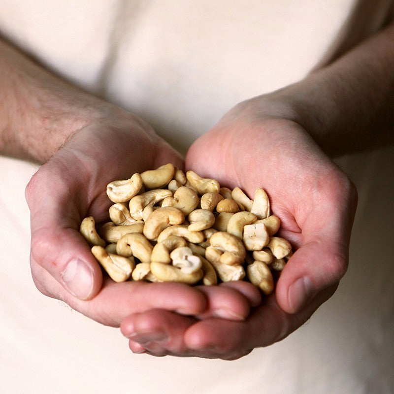 two hands holding cashew nuts